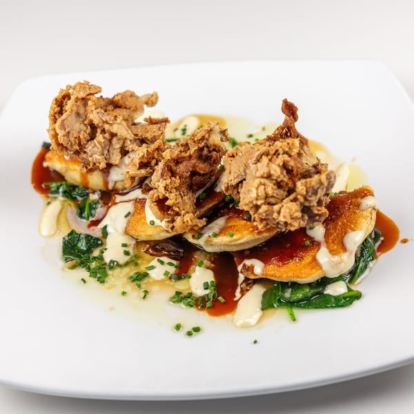 Crispy fried mushrooms on golden pancakes with spinach, rich sauces, and fresh chives.