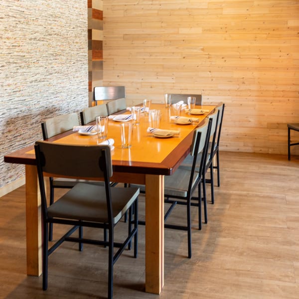 Set wooden dining table with chairs in a restaurant featuring textured and wood-paneled walls.