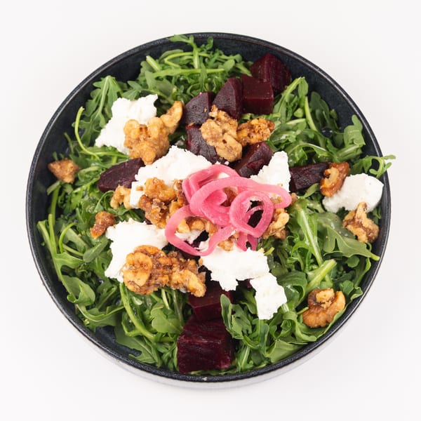 Vibrant arugula salad with beets, goat cheese, candied walnuts, and pickled onions.