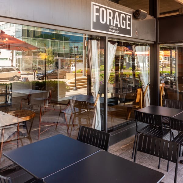 Forage Public House & Cafe sign above an outdoor patio with black tables and chairs.